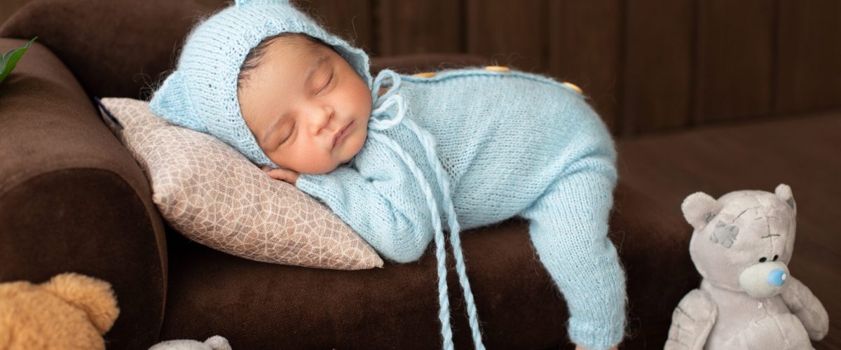 petit-bebe-garcon-joli-nouveau-ne-portant-canape-marron-bleu-crochete-pijama-entoure-jouets